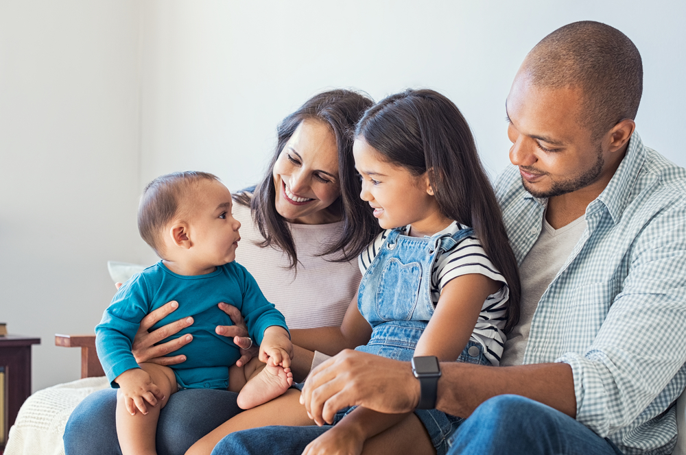 Pais sentados com bebê menino e menina.